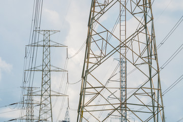 High voltage powerlines tower with cloudy and blue sky in background