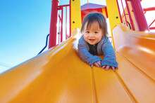 Mixed Race Toddler Boy Playing On A Slide At A Playground