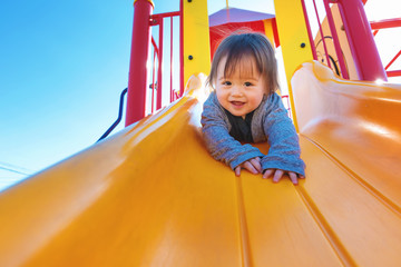 Wall Mural - Mixed race toddler boy playing on a slide at a playground