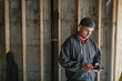 © Rob and Julia Campbell/Stocksy - Electrician man using mobile cell phone on jobsite