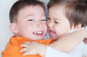 Wall Mural - happy kids, laughing children hugging each other, closeup portrait of boy and little girl, happiness in childhood of siblings