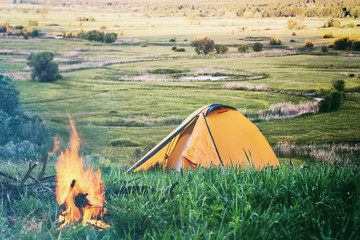 Wall Mural - orange tent with fire in field with green grass