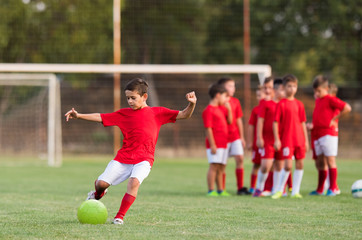 Wall Mural - Boy kicking football on the sports field