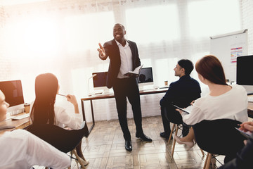 a black man talks to employees of a business office at a seminar.