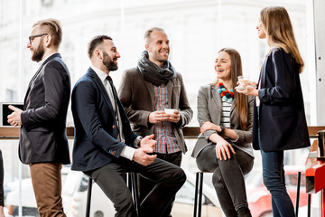 Business people having a conversation during the coffee break near the window in the cafe