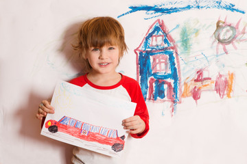 Cute little boy holds the drawing on paper