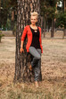 © Sa_Shiko - A smiling young blonde woman stands near a pine tree in the park.