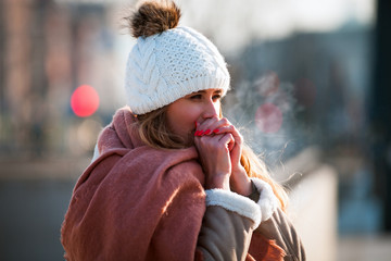 Woman breathing on her hands to keep them warm at cold winter