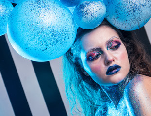 Young attractive girl in makeup, in glasses and balloons on the head