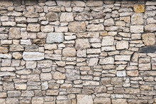 Close-up Textured Background Is An Irregular Natural Stone Wall Made Of Different Stones Without A Cement-type Bonding Mixture. Medieval Background