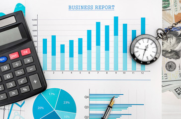 Financial graphs with calculator, pocket watch and money on the table.