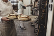 © Maskot - Baker holding bread on tray