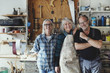 © Maskot - Portrait of male and female senior coworkers standing against tools at workshop