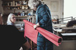 © Maskot - Female owner showing red rolled up fabric to colleagues at workshop