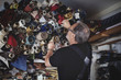 © Maskot - Low angle view of senior male owner looking at rolled fabrics in workshop