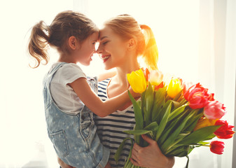 Wall Mural - happy mother's day! child daughter gives mother a bouquet of flowers to tulips.