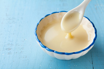 bowl with pouring condensed milk or evaporated milk.