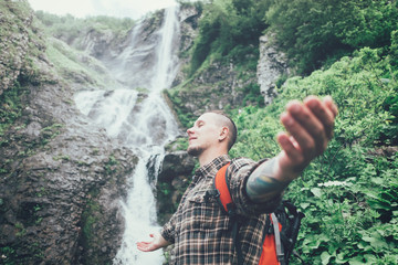 Wall Mural - Happy explorer man near the waterfall.