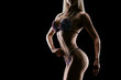 © USM Photography - Close-up photo perfect female bikini model posing on black background Attractive female athlete bodybuilder posing demonstrate her well trained body shape arms chest booty Copy space