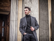 Handsome Bearded Young Man Outdoor In Winter Fashion, Wearing Black Turtleneck Sweater And Woolen Blazer Jacket In City Setting