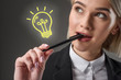 © LIGHTFIELD STUDIOS - portrait of beautiful young businesswoman with pen and light bulb symbol, isolated on grey
