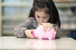 © Nattanon - Kid has saved money completed  and opening piggy bank pink in the Library.
