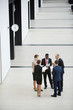 © pressmaster - Group of five business partners in suits standing in large hall and discussing their reports for conference