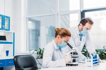 Wall Mural - scientists in medical masks and goggles working on scientific research in laboratory