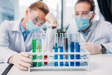 Wall Mural - selective focus of scientific researchers in goggles and medical masks looking at reagents in tubes in lab