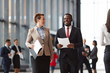 © pressmaster - Contemporary intercultural colleagues in formalwear walking inside airport and having talk