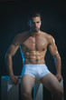 © Svitlana - Fashion portrait of sexy male fitness model in underwear. Male swimwear & underwear concept. Muscular male model in trendy white underwear. Handsome sexy muscular naked man posing on a dark background