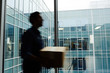 © pressmaster - Defocused courier with package walking along modern office building window inside