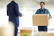 © pressmaster - Young courier carrying big box to office worker while helping him to relocate