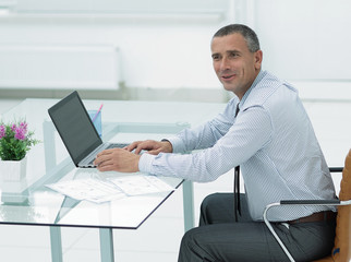 smiling businessman sitting at Desk and looking at camera