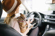 © karrastock - Beautiful young woman using her mobile phone in the car, With chihuhua dog