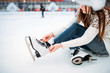 Young woman ties the shoelaces on skates
