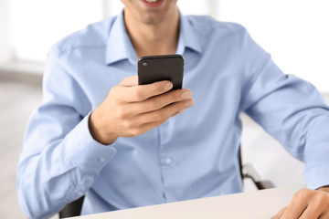 Wall Mural - Young man using phone at table indoors