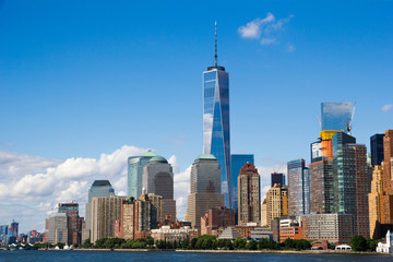 New York’s Manhattan cityscape and famous skyscrapers look striking and colorful reflecting the bright blue late afternoon sky and clouds, as seen from Hudson River