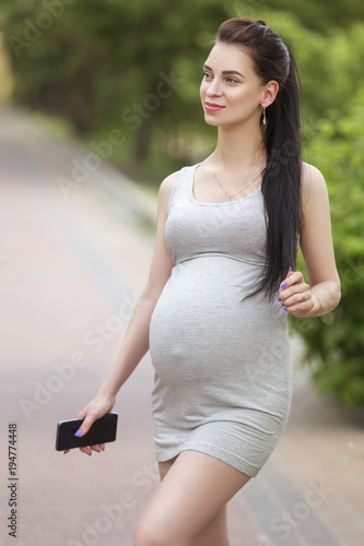 Cute young brunette sexy pregnant woman with long hair in ponytail and ...