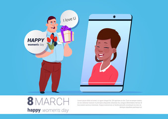 Wall Mural - Man Greeting Girl White International Women Day Online With Smart Phone Holding Flowers And Present Over Background With Copy Space Flat Vector Illustration