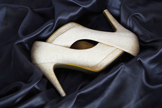 Pair of Gold High Heels in the silk box. The Luxury background.