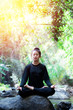 Asian beautiful young girl doing yoga on rock in stream forest
