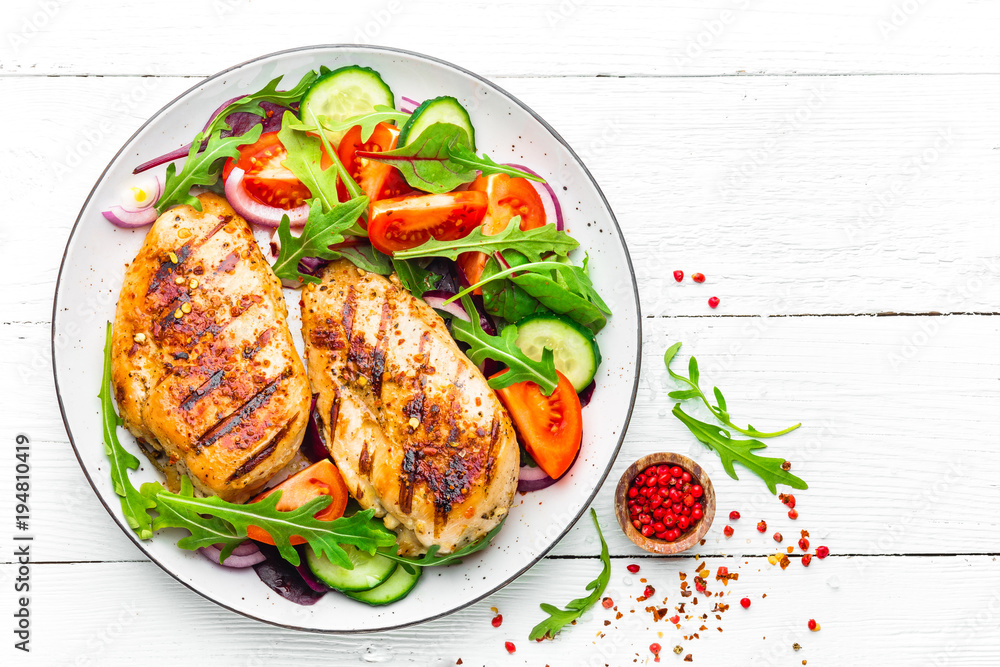 Grilled chicken breast. Fried chicken fillet and fresh vegetable salad of tomatoes, cucumbers and arugula leaves. Chicken meat salad. Healthy food. Flat lay. Top view. White background - obrazy, fototapety, plakaty 