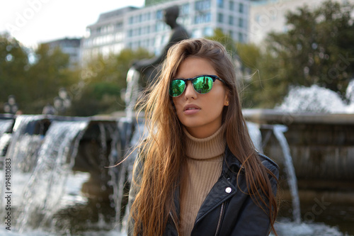 Fotografie, Obraz Chica joven con gafas delante de una fuente en la ciudad