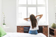 © F8  \ Suport Ukraine - Young happy woman woke up in the morning in the bedroom by the window back view