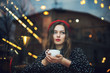 Young beautiful fashionable girl with red lips, wearing french style beret and polka dot blouse drinks coffee or tea in cafe. Model looking up. Copy, empty space for text