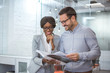 © Bojan - Cheerful business people looking at document while standing in modern office.