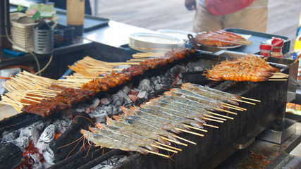 singapore - apr 3rd, 2015: delicious tasty skewers of chicken cook over hot coals in singapore's sat