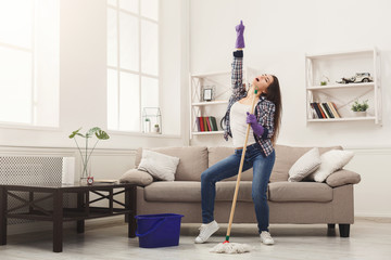 happy woman cleaning home with mop and having fun
