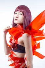 Asian Woman Cosplayer With Futuristic Costume In Red, Made With Pvc Plastics And Transparencies. Oriental Girl